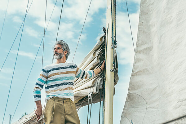 Eleganter Sommerlook für Herren mit weisser Strickjacke und leichter Stoffhose